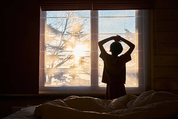 Silhuett av ett barn vid fönstret i morgonljus